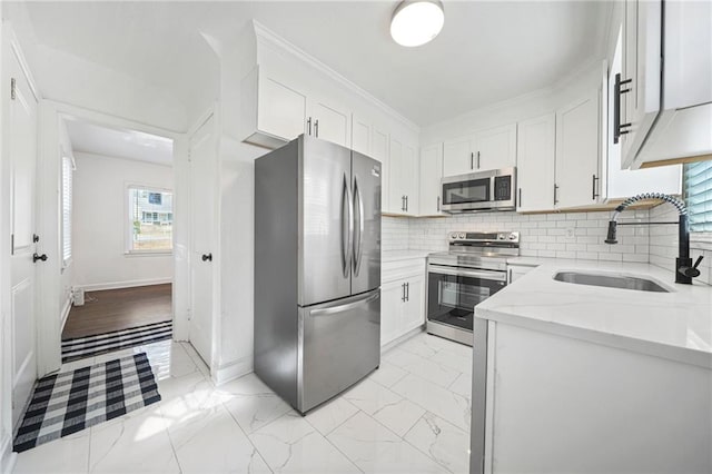 kitchen featuring sink, stainless steel appliances, light stone countertops, white cabinets, and decorative backsplash