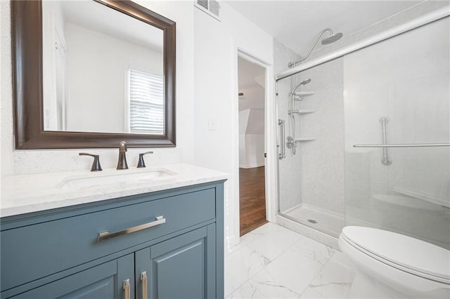 bathroom featuring vanity, a shower with shower door, and toilet