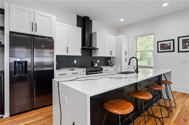 210 Locust St NE, Atlanta, GA 30317 - kitchen featuring wall chimney range hood, light wood-type flooring, a sink, refrigerator with ice dispenser, and an island with sink