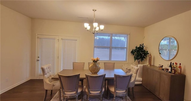 dining area with dark hardwood / wood-style floors and an inviting chandelier