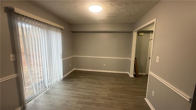 unfurnished room featuring a textured ceiling and dark wood-type flooring