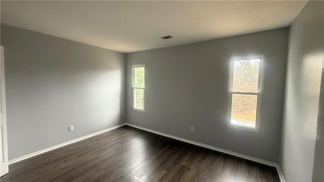 empty room featuring dark hardwood / wood-style flooring and a wealth of natural light