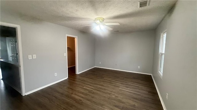 empty room with ceiling fan, dark wood-type flooring, and a textured ceiling