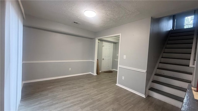 basement featuring dark hardwood / wood-style flooring and a textured ceiling