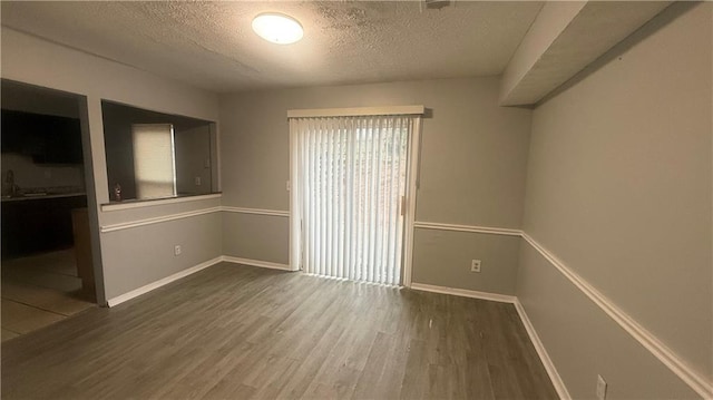 empty room featuring wood-type flooring and a textured ceiling