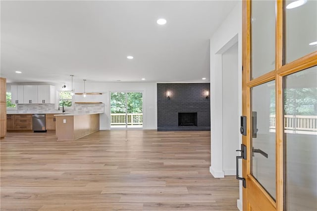 6142 Hutchins Dr, Buford, GA 30518 - kitchen with a sink, stainless steel dishwasher, open floor plan, light wood-style floors, and light countertops
