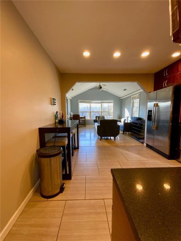 hallway featuring lofted ceiling, arched walkways, baseboards, and recessed lighting