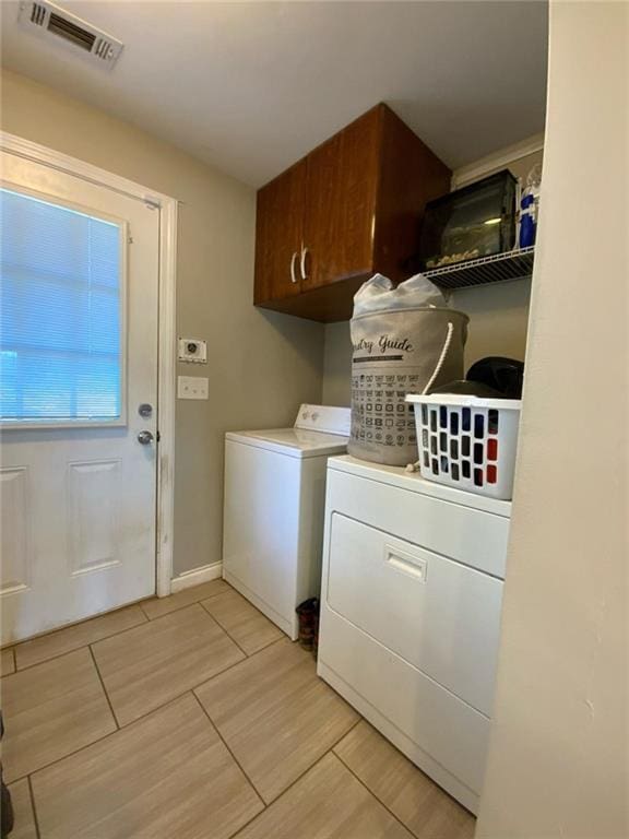 laundry room with visible vents, washing machine and clothes dryer, cabinet space, and baseboards