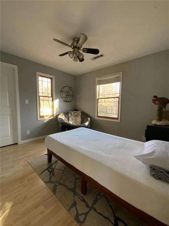 bedroom with ceiling fan, baseboards, visible vents, and light wood-style floors