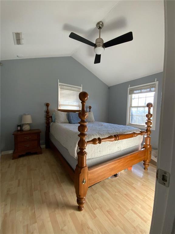 bedroom featuring ceiling fan, visible vents, vaulted ceiling, and wood finished floors