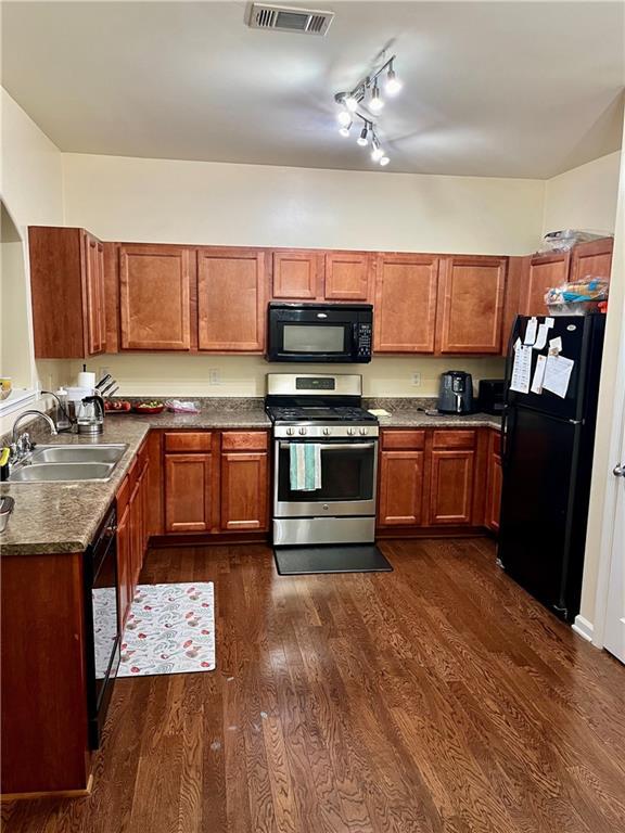 kitchen featuring black appliances, rail lighting, sink, and dark wood-type flooring