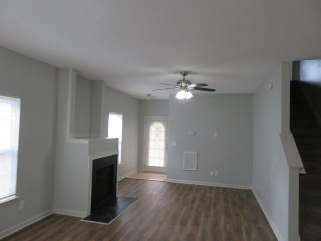 unfurnished living room with dark hardwood / wood-style flooring and ceiling fan