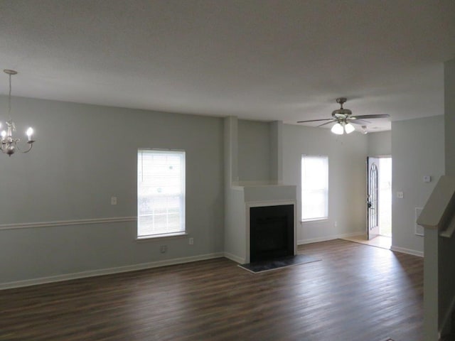 unfurnished living room featuring ceiling fan with notable chandelier and dark hardwood / wood-style floors