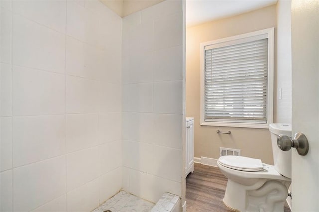 bathroom featuring tiled shower, wood-type flooring, and toilet