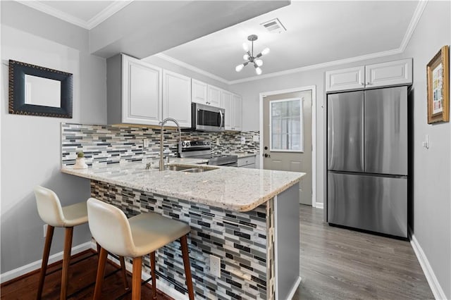 kitchen featuring stainless steel appliances, a kitchen breakfast bar, white cabinets, and kitchen peninsula