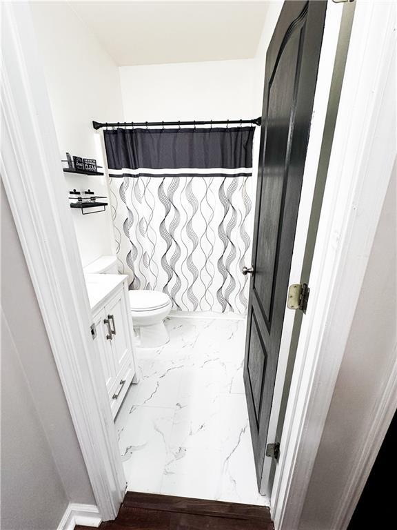 full bath featuring marble finish flooring, toilet, vanity, and a shower with shower curtain