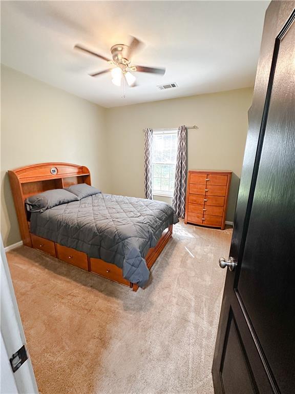 bedroom with light colored carpet, ceiling fan, and baseboards