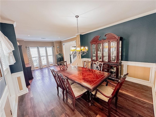 dining space with a chandelier, a wainscoted wall, dark wood-style flooring, and crown molding