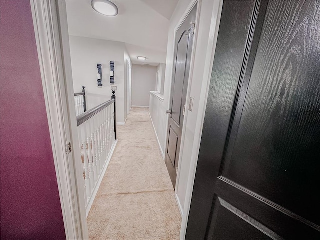 corridor featuring light colored carpet and baseboards