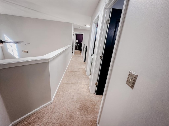 hallway featuring light colored carpet, baseboards, and an upstairs landing