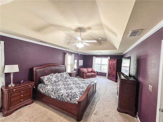bedroom with light colored carpet, a tray ceiling, ornamental molding, and a ceiling fan