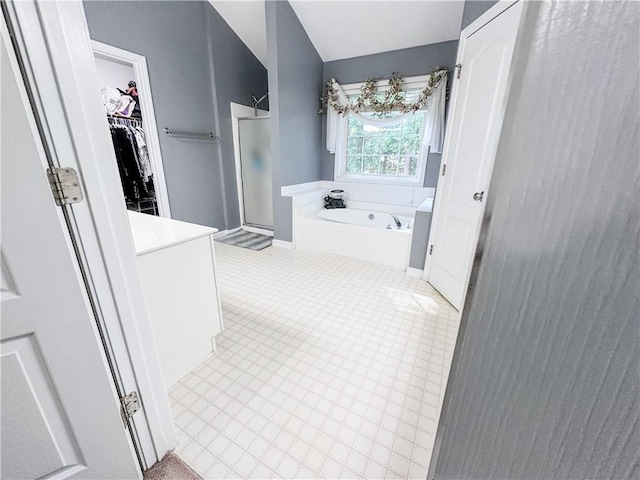 bathroom featuring a shower stall, a garden tub, a spacious closet, and tile patterned flooring