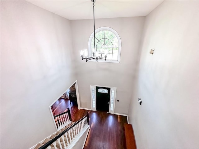 foyer entrance with a chandelier, wood finished floors, stairway, and baseboards