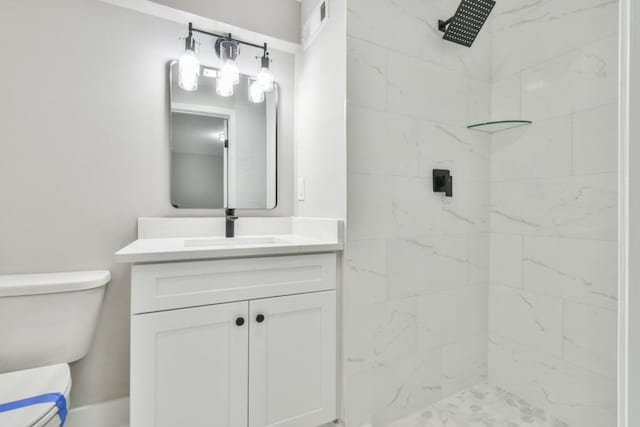 bathroom featuring tiled shower, vanity, and toilet