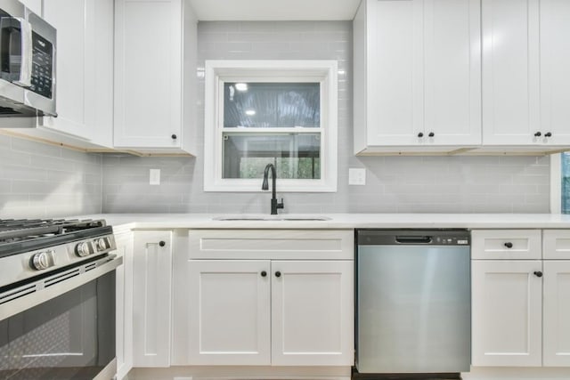 kitchen featuring sink, stainless steel appliances, white cabinets, and tasteful backsplash