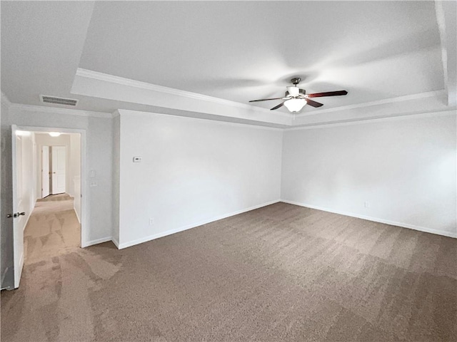 carpeted spare room featuring baseboards, visible vents, ceiling fan, a tray ceiling, and crown molding