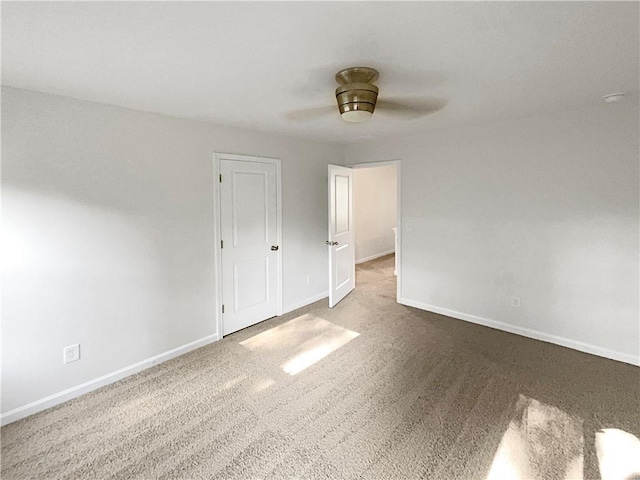 carpeted spare room with a ceiling fan and baseboards