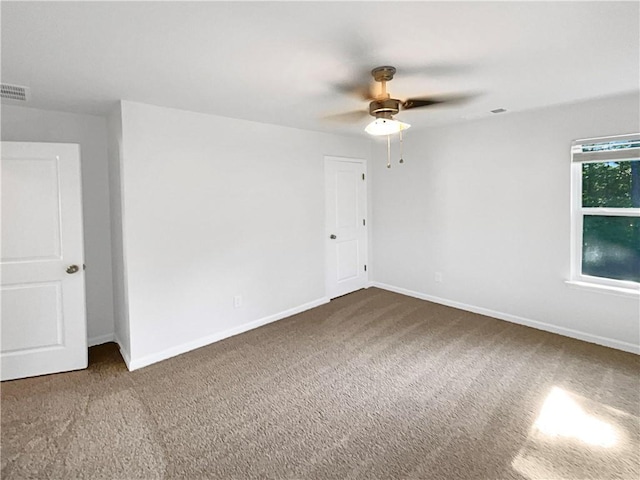 spare room with a ceiling fan, carpet flooring, visible vents, and baseboards