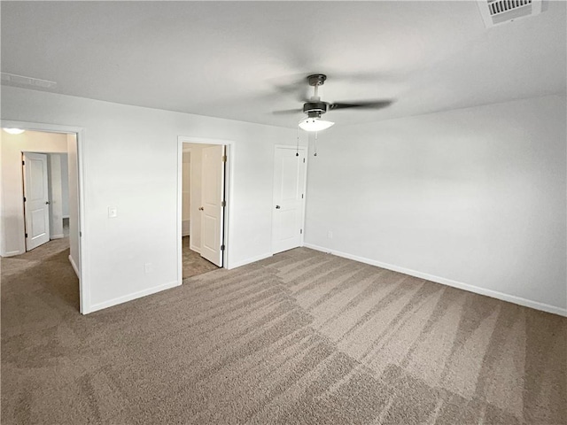 unfurnished bedroom with baseboards, visible vents, dark colored carpet, and a ceiling fan