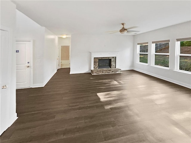 unfurnished living room featuring dark wood-style floors, ceiling fan, a fireplace, and baseboards