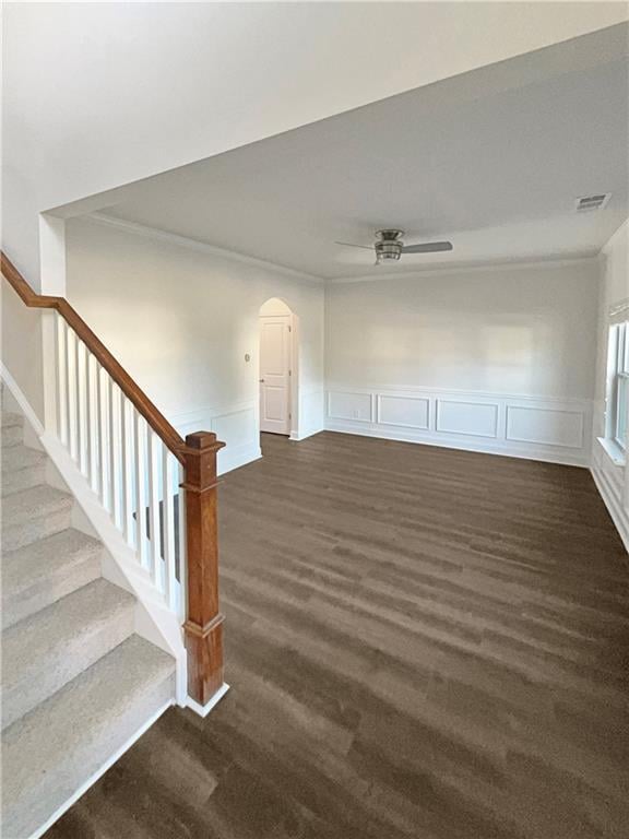 empty room with visible vents, arched walkways, ceiling fan, dark wood-style flooring, and stairs