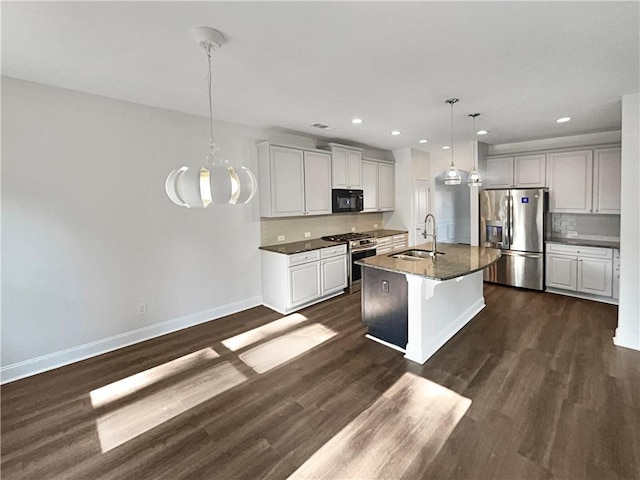 kitchen featuring stainless steel appliances, a sink, baseboards, a center island with sink, and pendant lighting