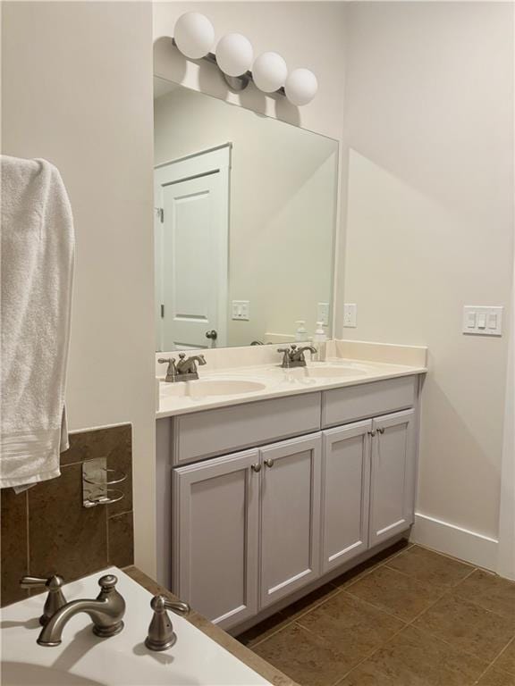 bathroom with double vanity, baseboards, and tile patterned flooring