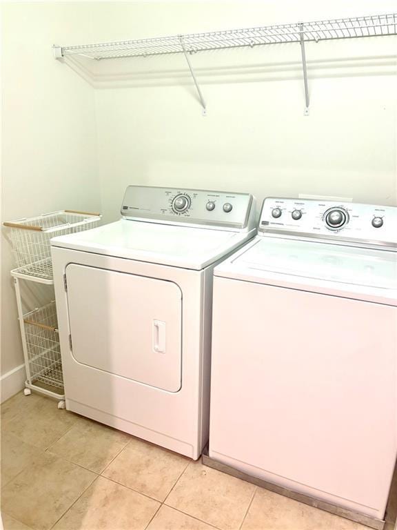 washroom featuring separate washer and dryer, light tile patterned floors, and baseboards