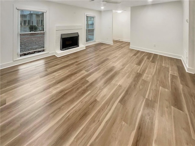 unfurnished living room with a fireplace, baseboards, and wood finished floors