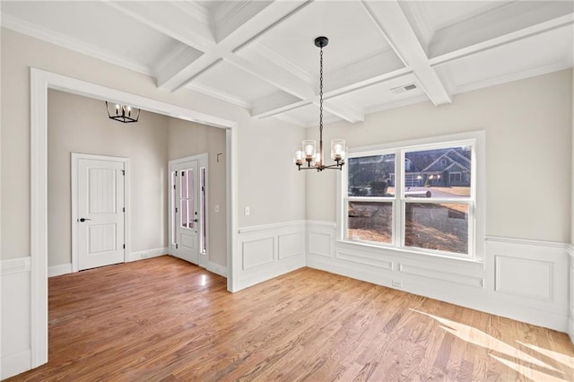 unfurnished dining area with beam ceiling, coffered ceiling, a notable chandelier, and wood-type flooring