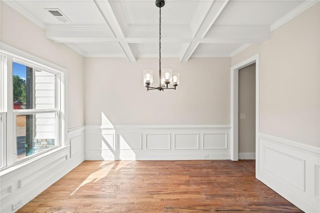 unfurnished dining area featuring a notable chandelier, hardwood / wood-style flooring, beamed ceiling, and coffered ceiling