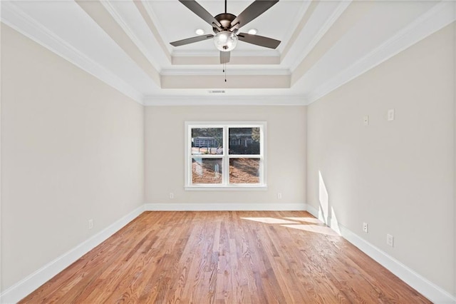 spare room with crown molding, ceiling fan, light wood-type flooring, and a raised ceiling