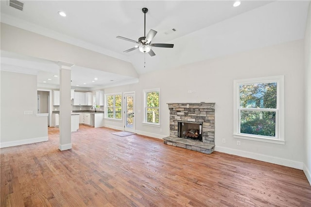 unfurnished living room with a stone fireplace, light hardwood / wood-style flooring, ceiling fan, and a wealth of natural light