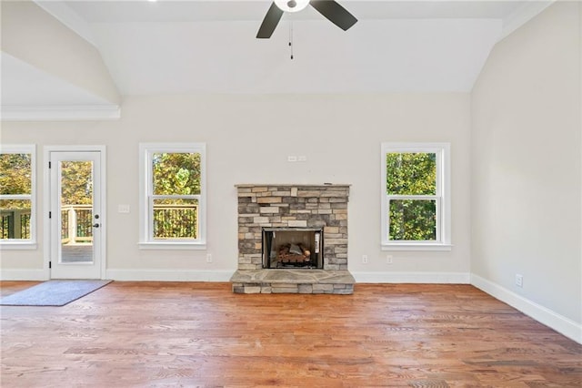 unfurnished living room featuring ceiling fan, a stone fireplace, wood-type flooring, and lofted ceiling