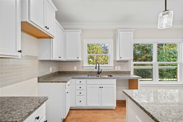 kitchen featuring light stone countertops, sink, and white cabinetry