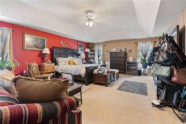 bedroom with a ceiling fan, light carpet, and a tray ceiling