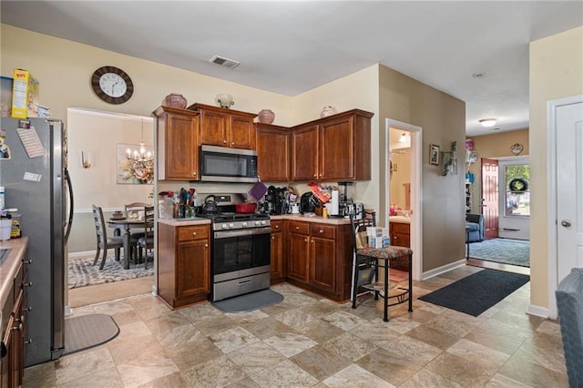 kitchen featuring visible vents, stainless steel appliances, light countertops, a chandelier, and baseboards