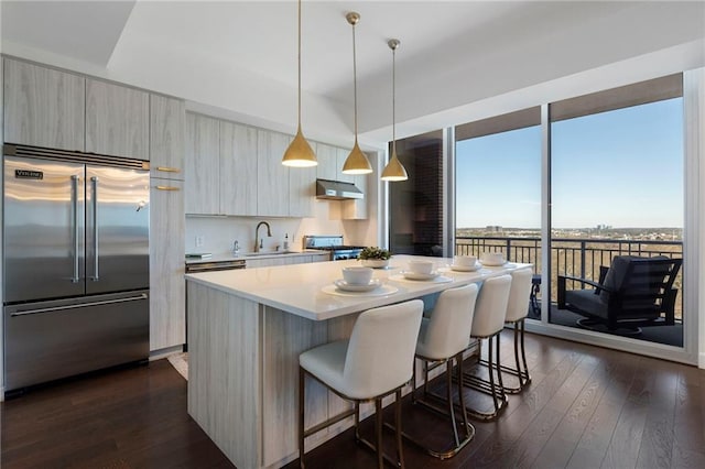 kitchen with built in refrigerator, pendant lighting, a center island, dark wood-type flooring, and sink