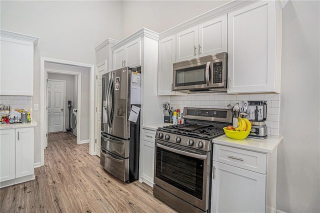 kitchen with light wood finished floors, light countertops, decorative backsplash, stainless steel appliances, and white cabinetry