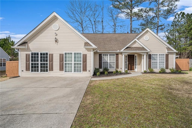 view of front of home with a front yard, fence, driveway, and roof with shingles